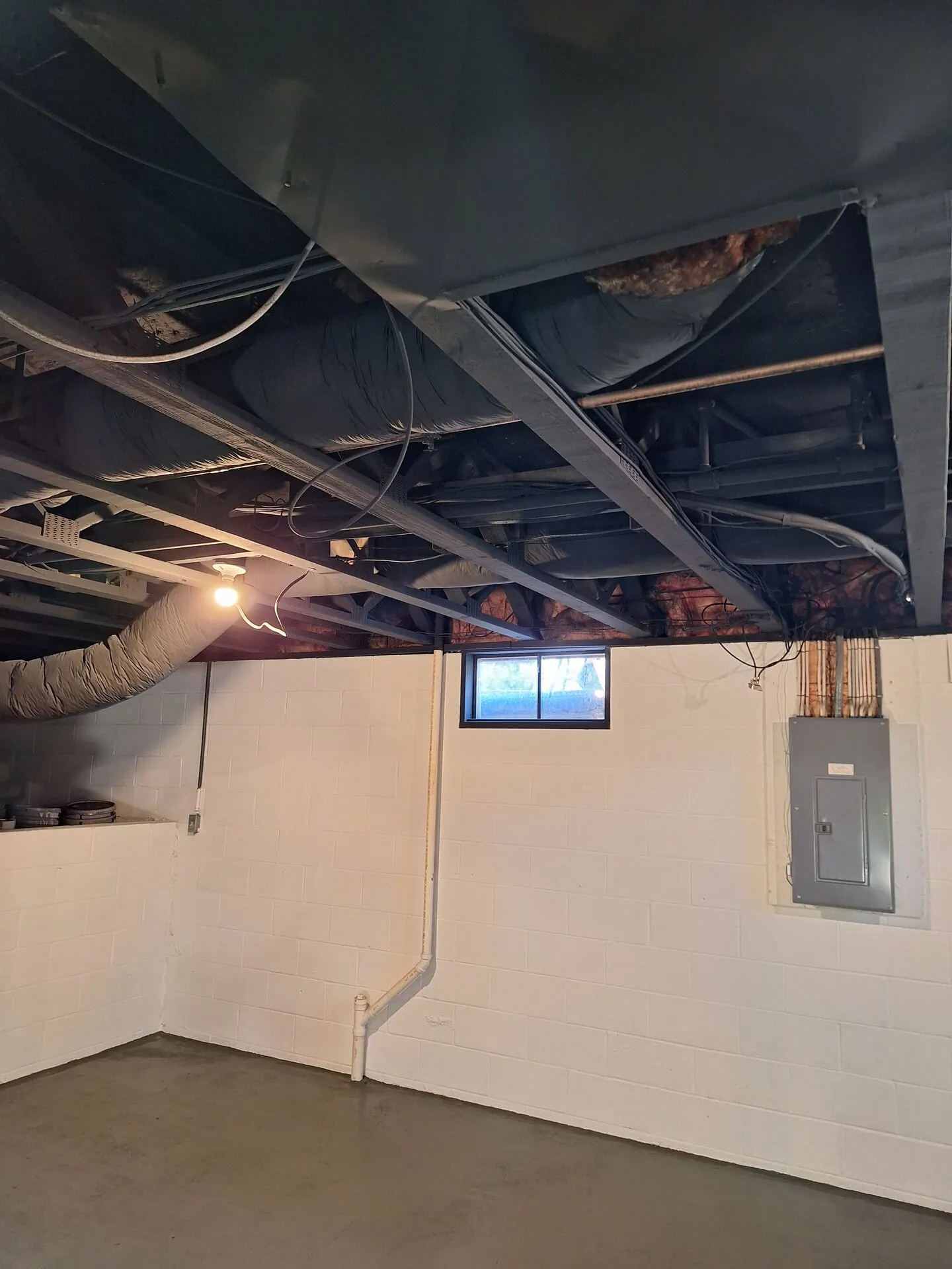 Basement with walls painted white and exposed ceiling painted black