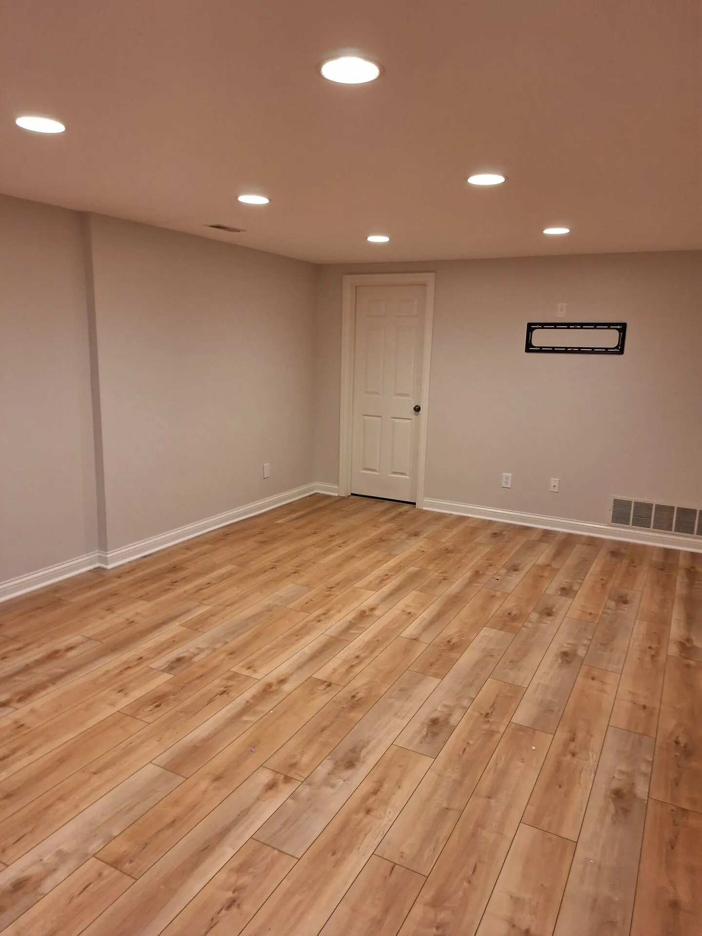 Finished basement painted warm beige with recessed lighting