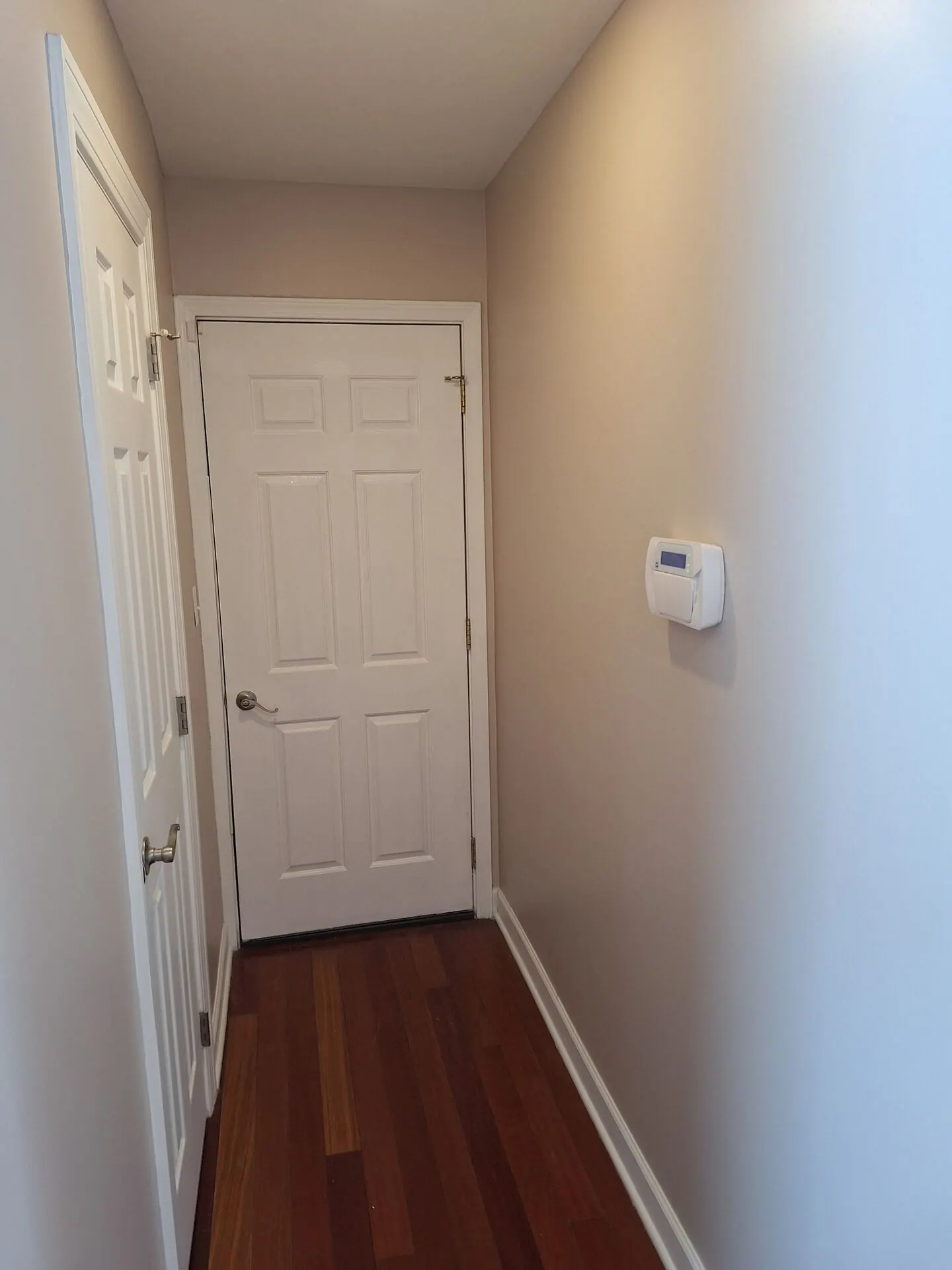 Narrow hallway painted warm beige with white door