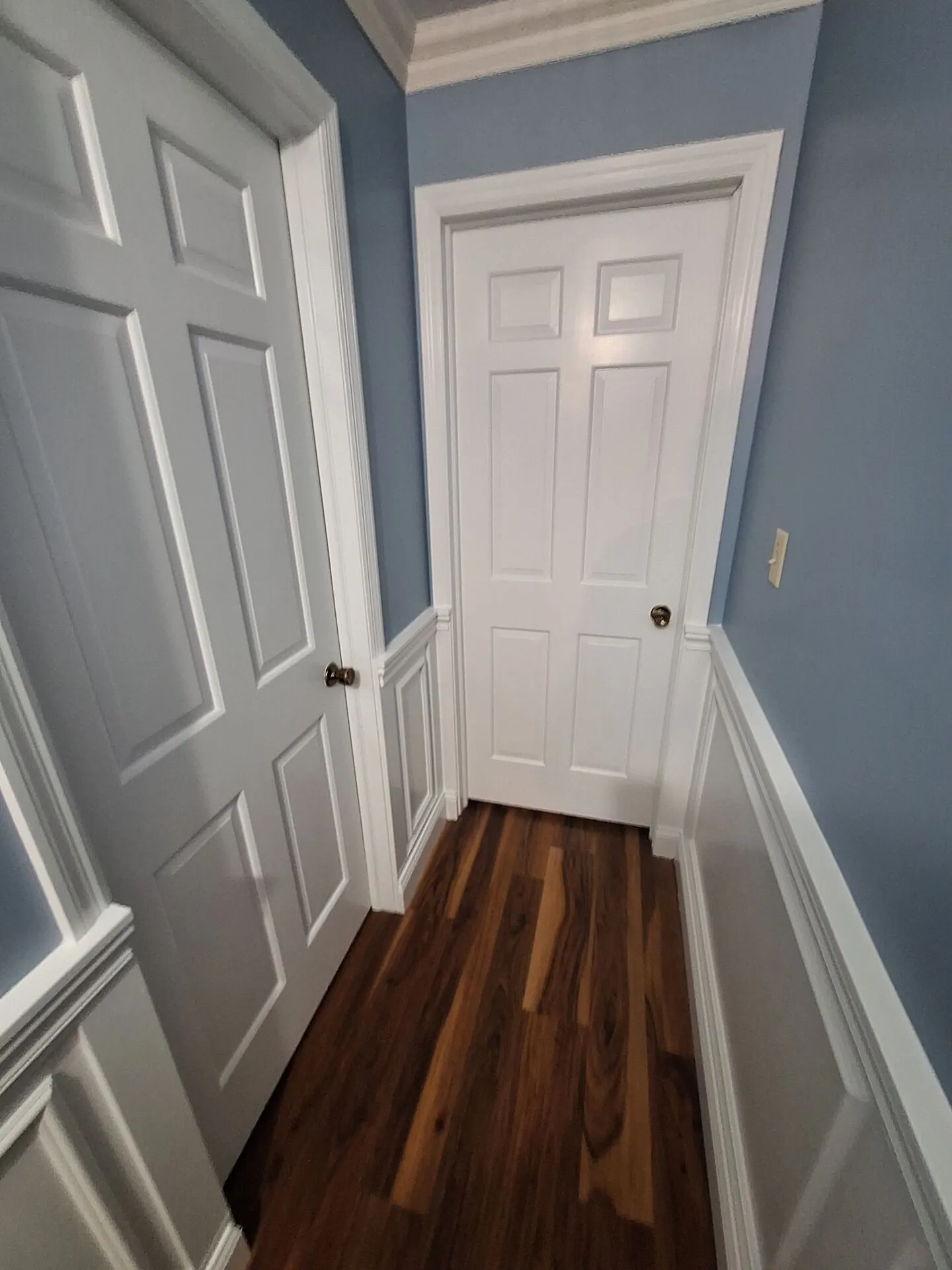 Blue-gray hallway with white doors and wainscoting