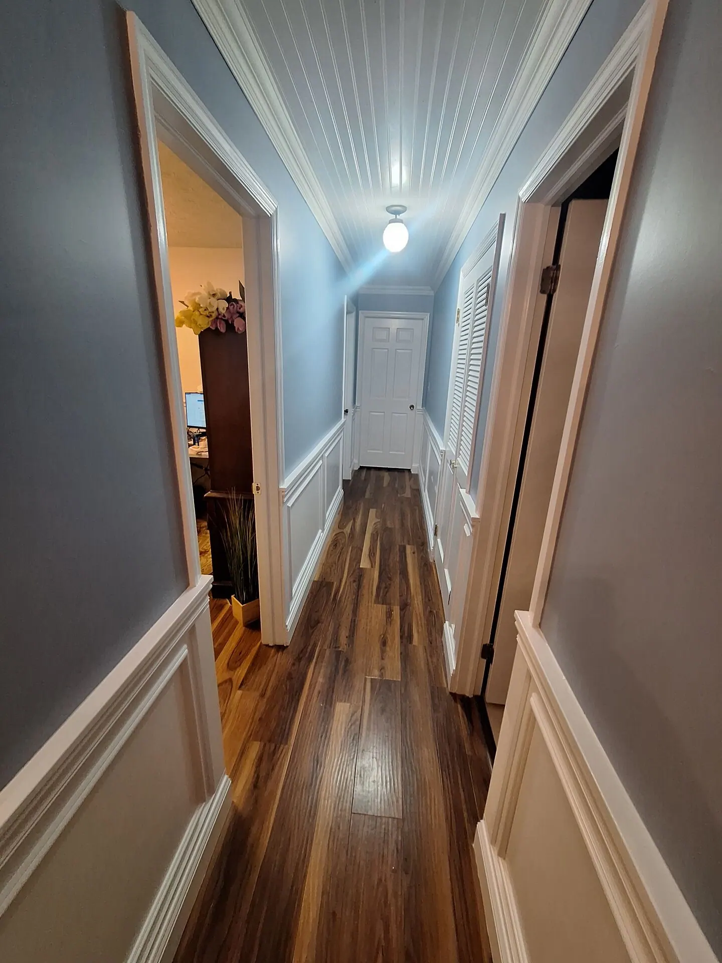 Hallway with blue-gray walls, white wainscoting and beadboard ceiling
