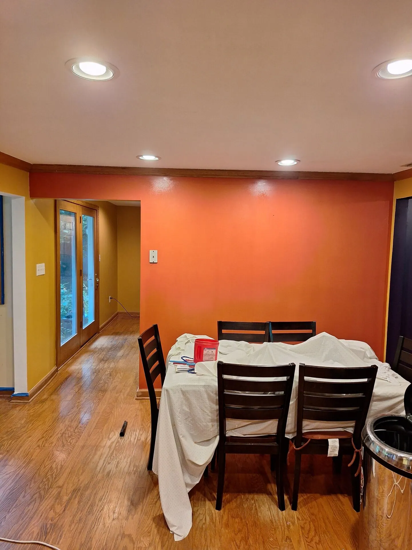 Dining room painted bold burnt orange with yellow accent wall