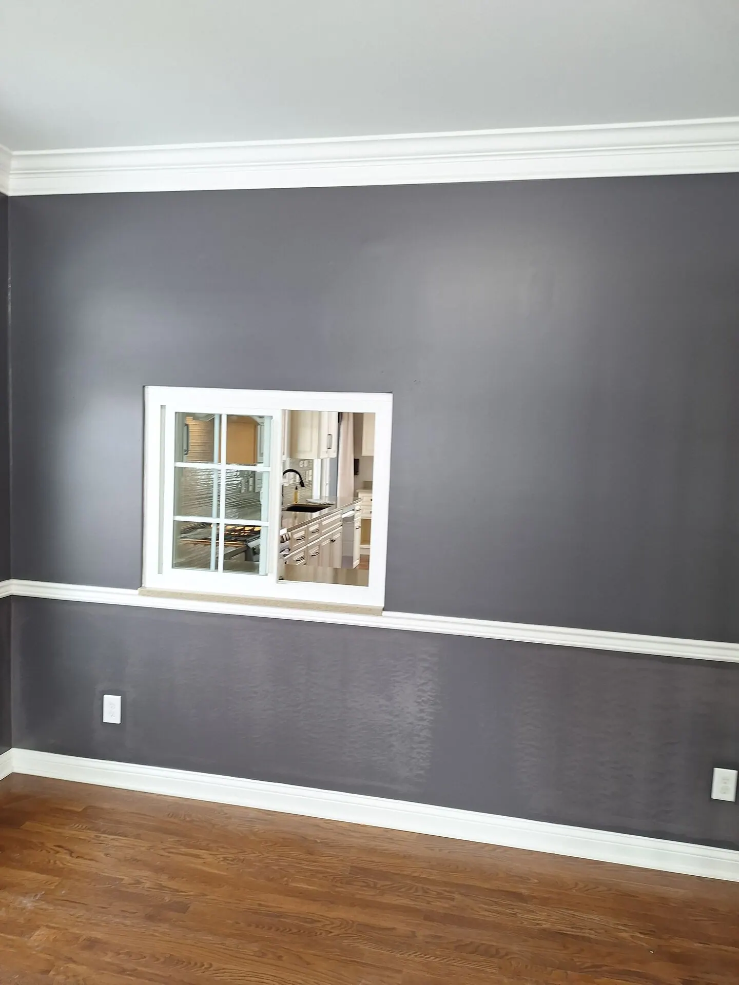 Dining room painted charcoal gray with white chair rail and crown molding
