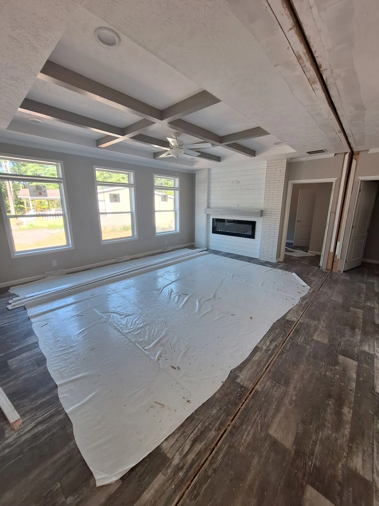 Living room with coffered ceiling during interior painting, floors covered