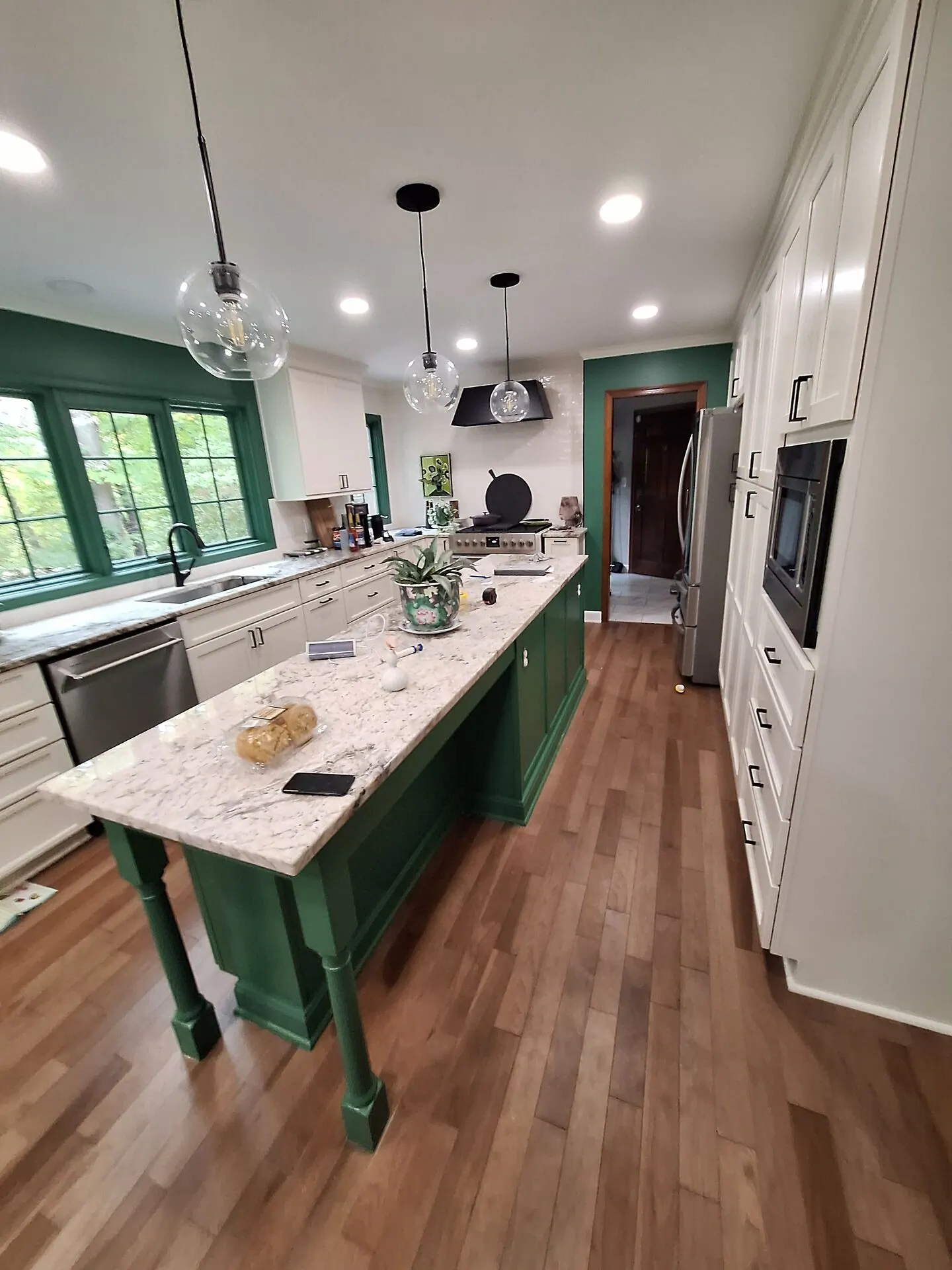 Kitchen with emerald green island and window trim beside white cabinets