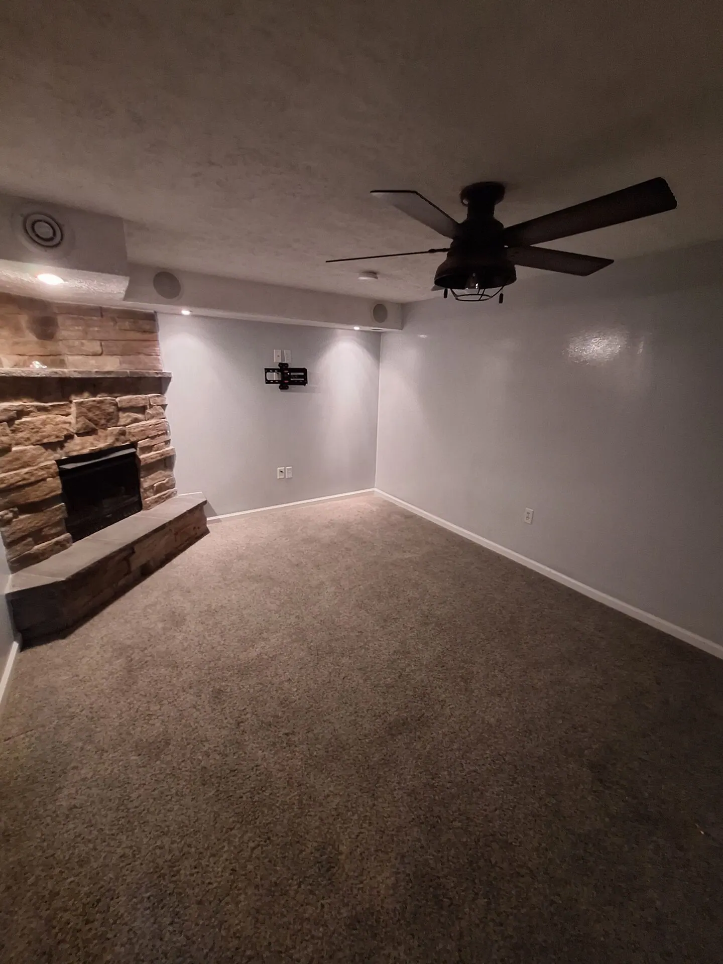 Basement family room painted light gray with stone fireplace