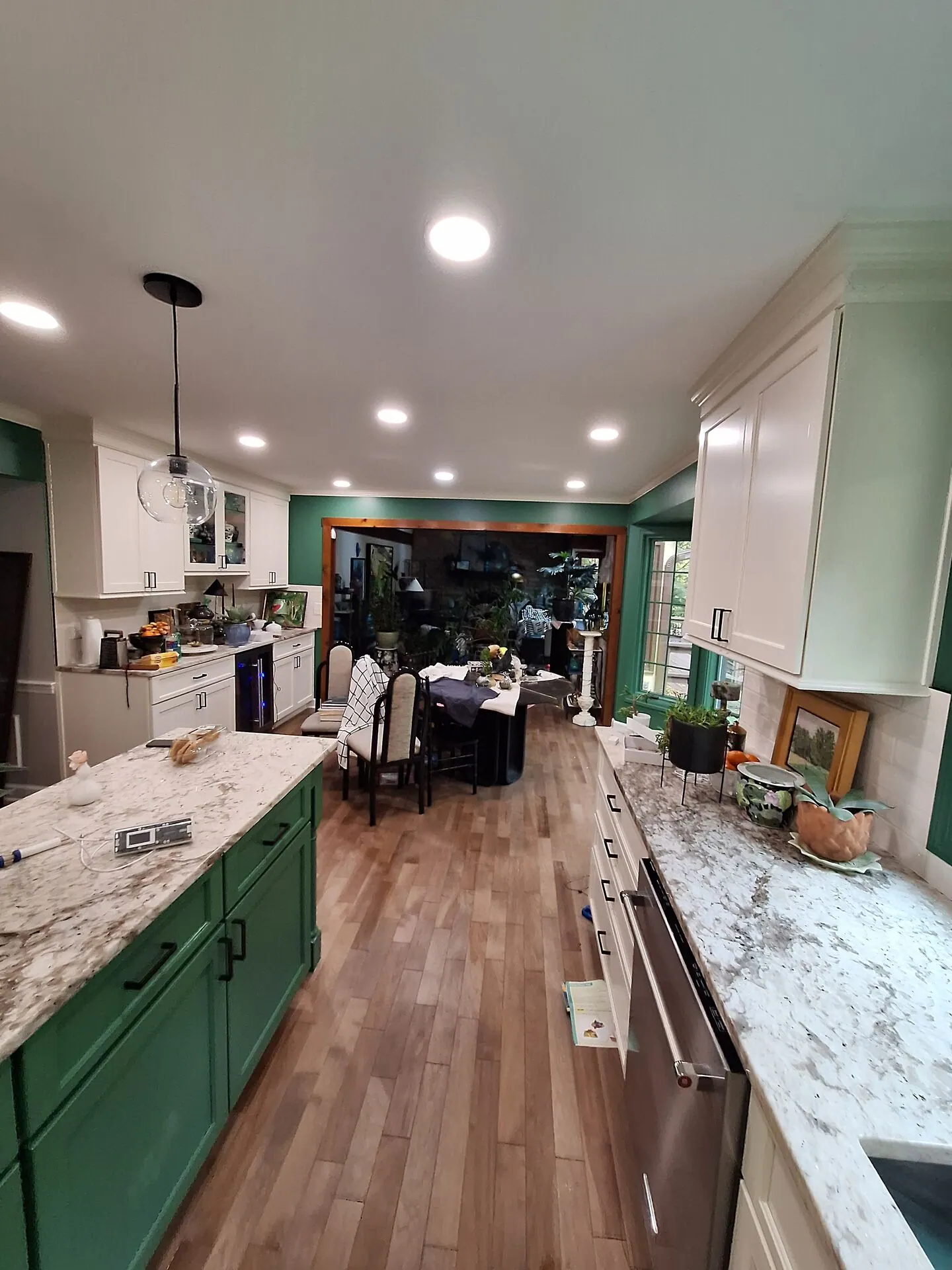 Long kitchen with green painted island and white perimeter cabinets