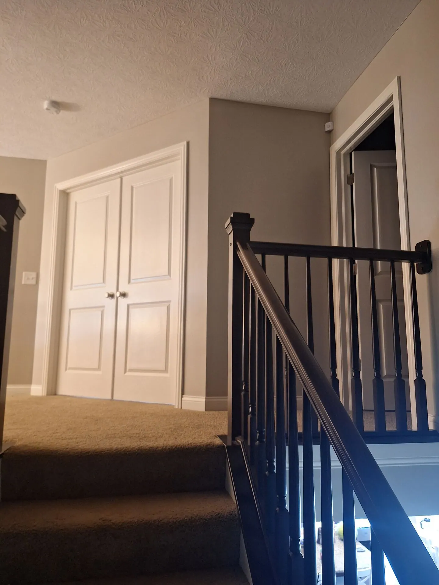Upstairs landing with black railing and greige walls