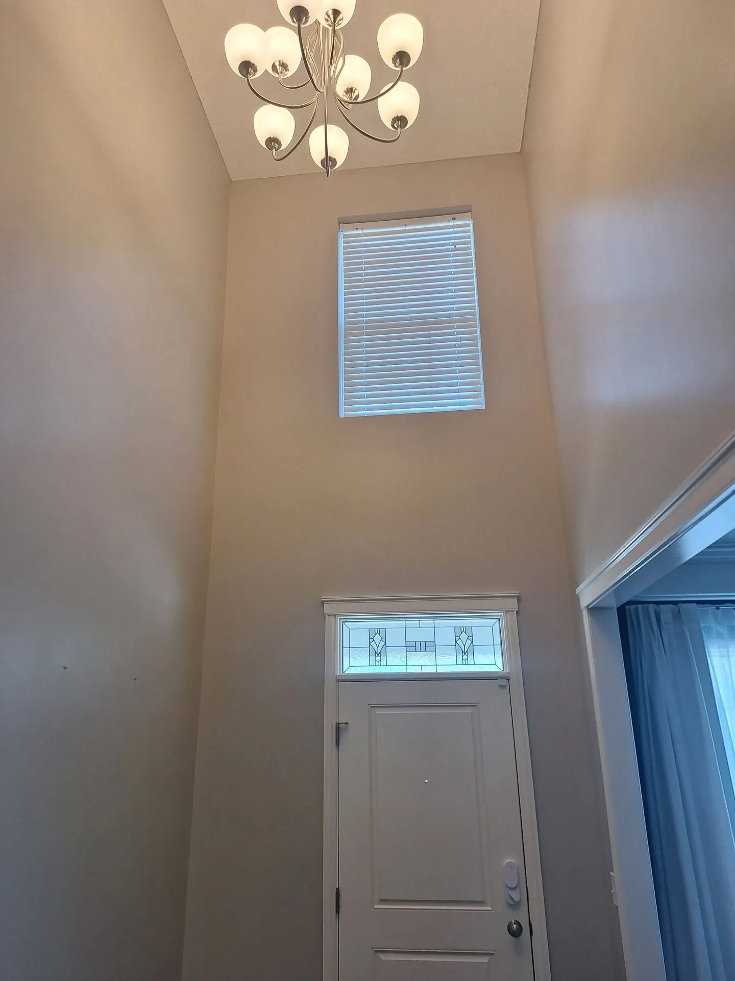 Two-story entry painted warm greige with chandelier