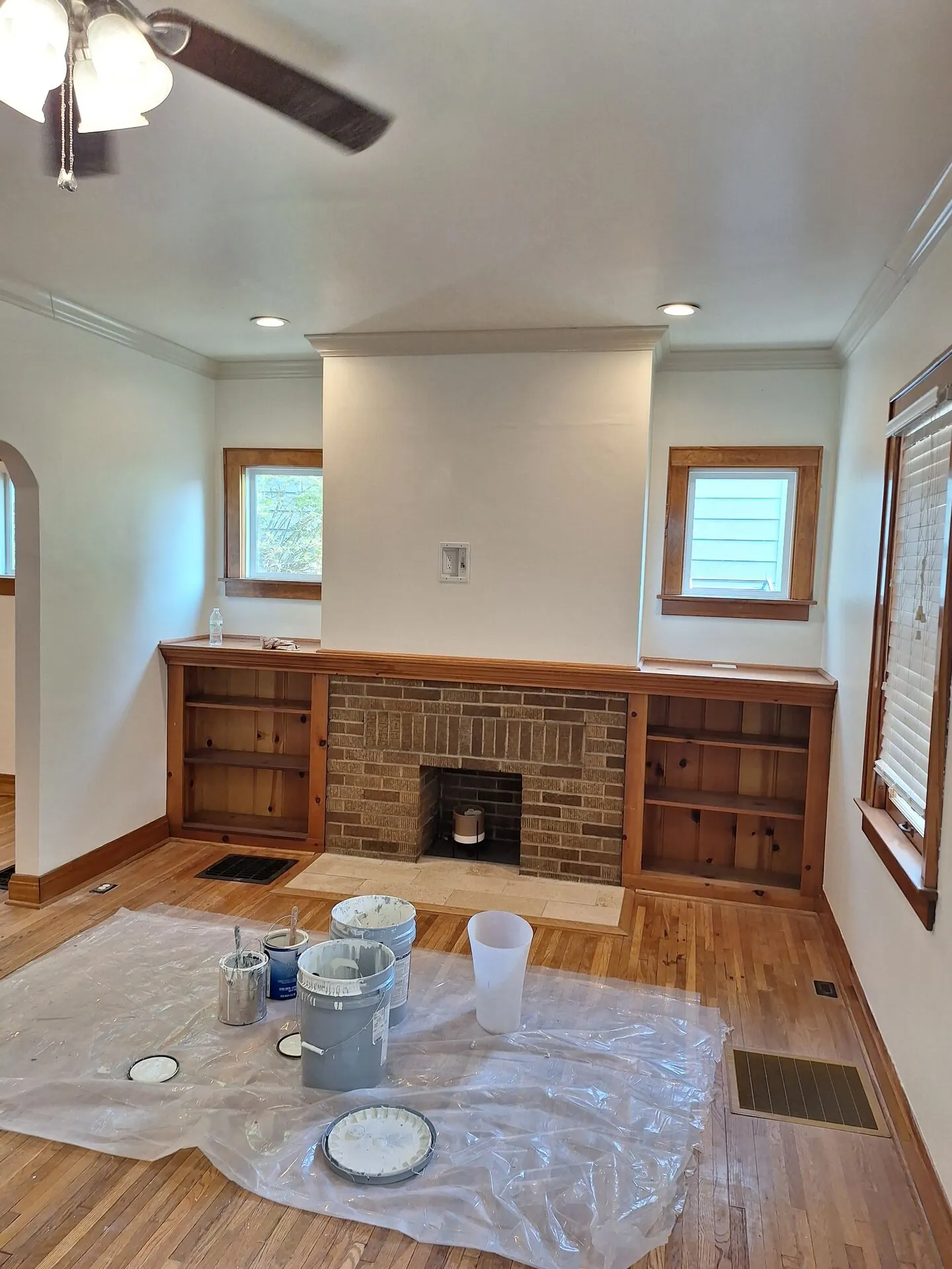Living room with brick fireplace and built-ins during interior repaint, floors protected
