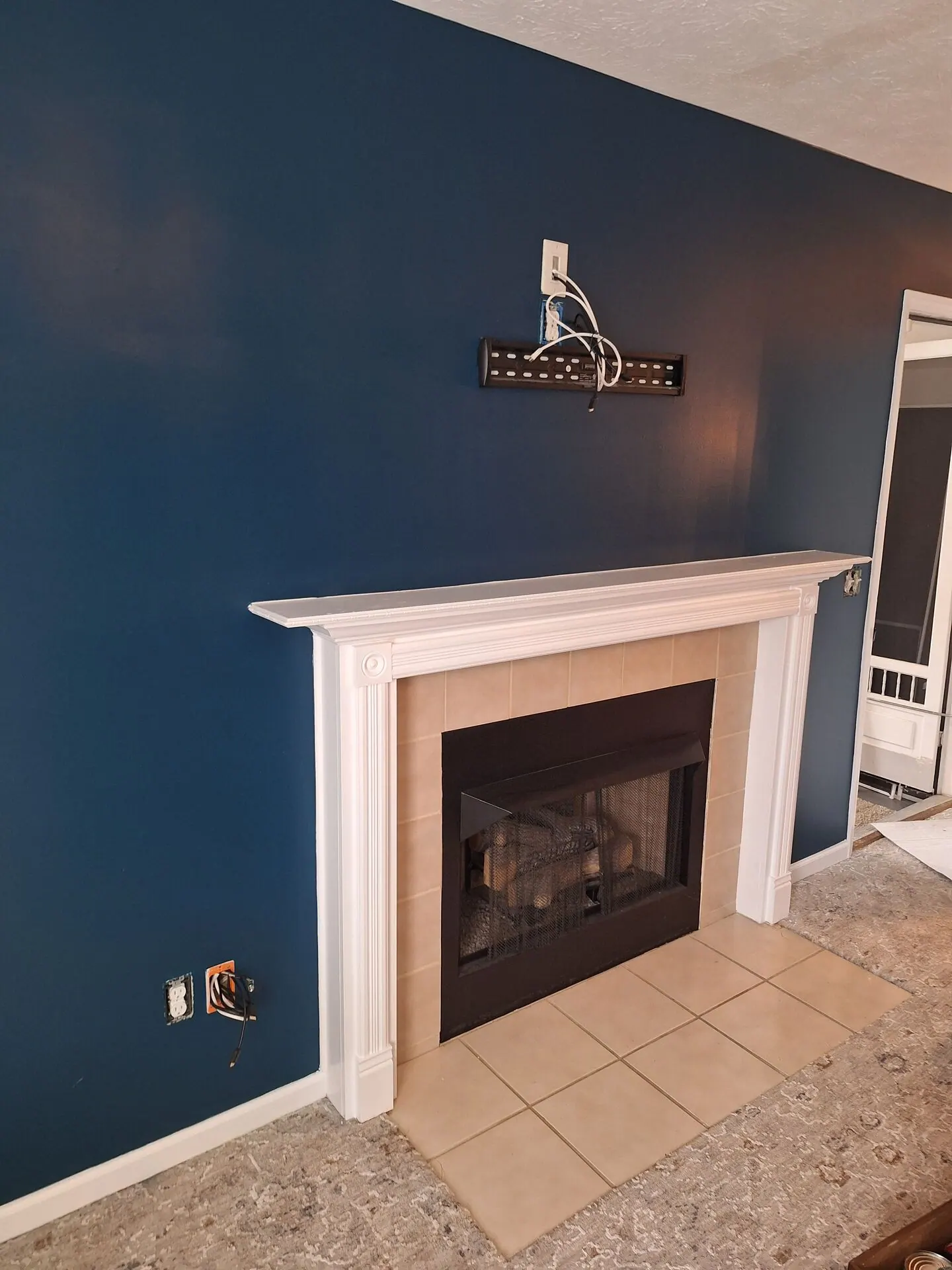 Living room painted deep navy blue with white fireplace mantel
