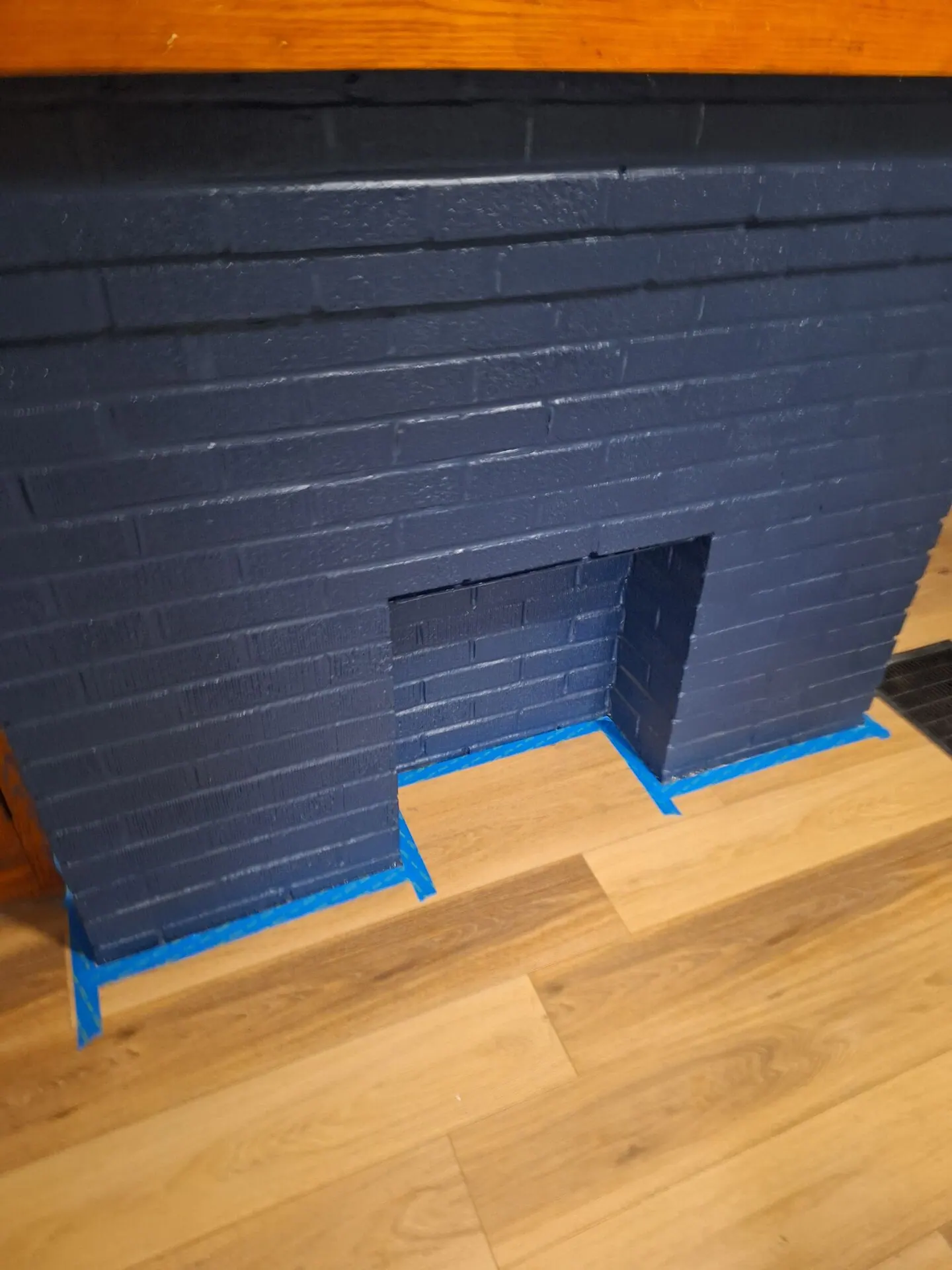 Brick fireplace painted deep navy blue with crisp lines at the floor