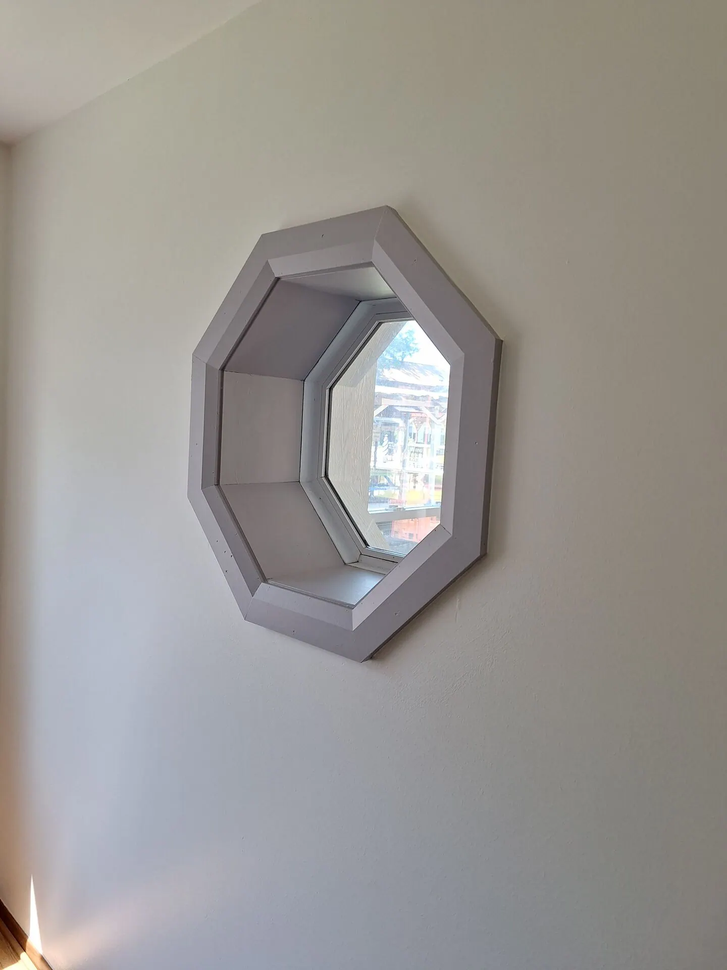 Octagon window with gray-painted trim on a greige wall