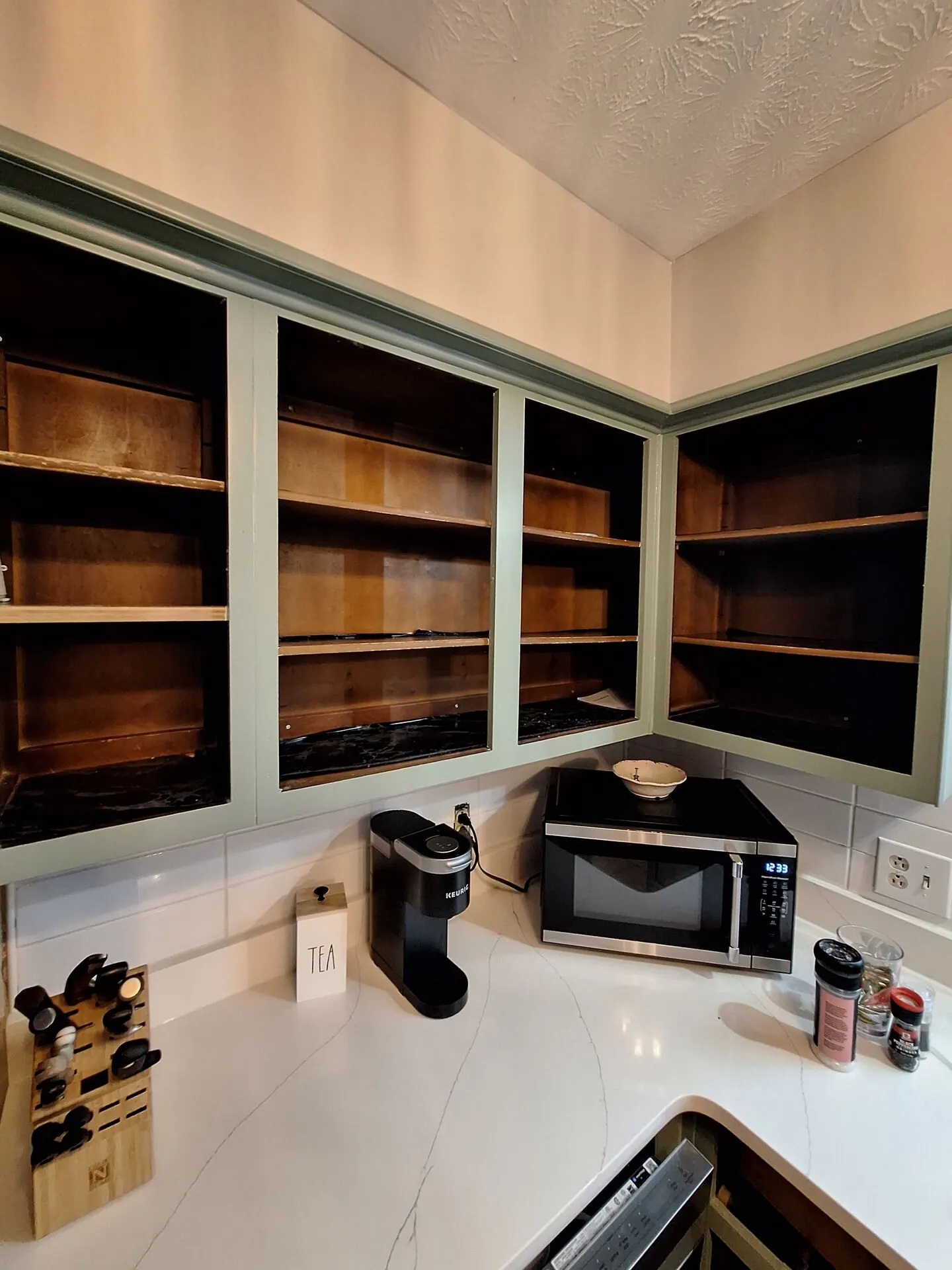 Kitchen cabinet boxes painted sage green with doors removed