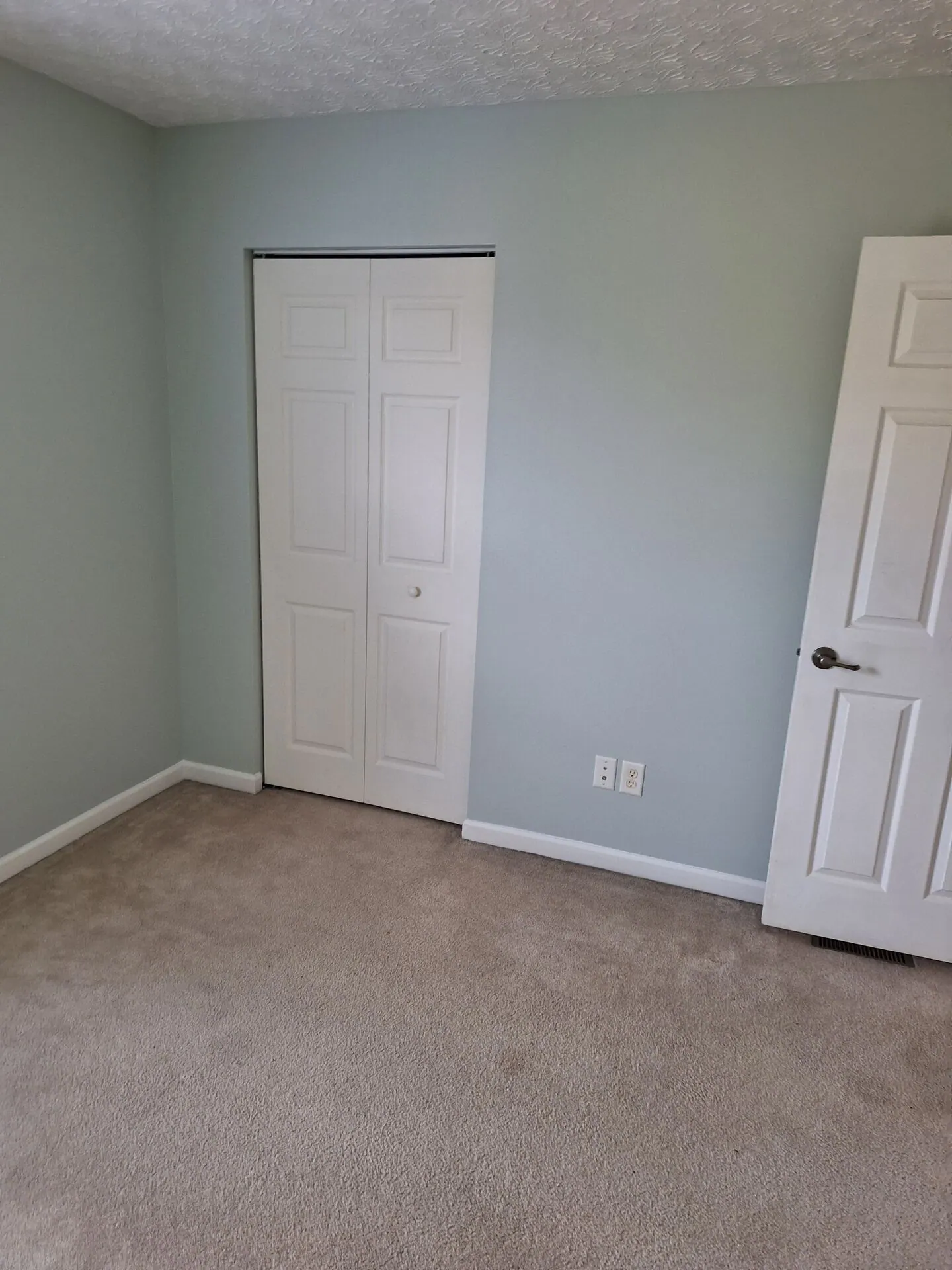 Bedroom painted soft seafoam green with white closet doors