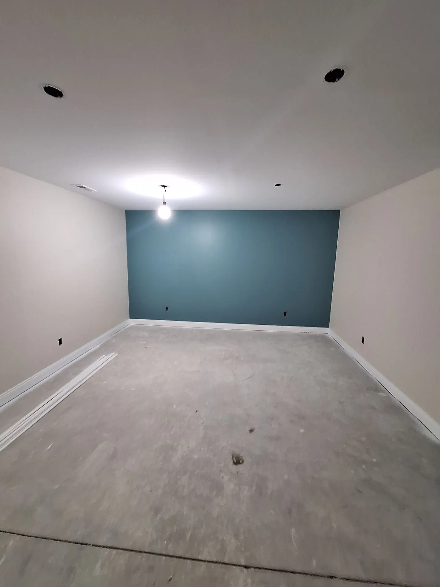 Basement room with deep teal accent wall and cream walls