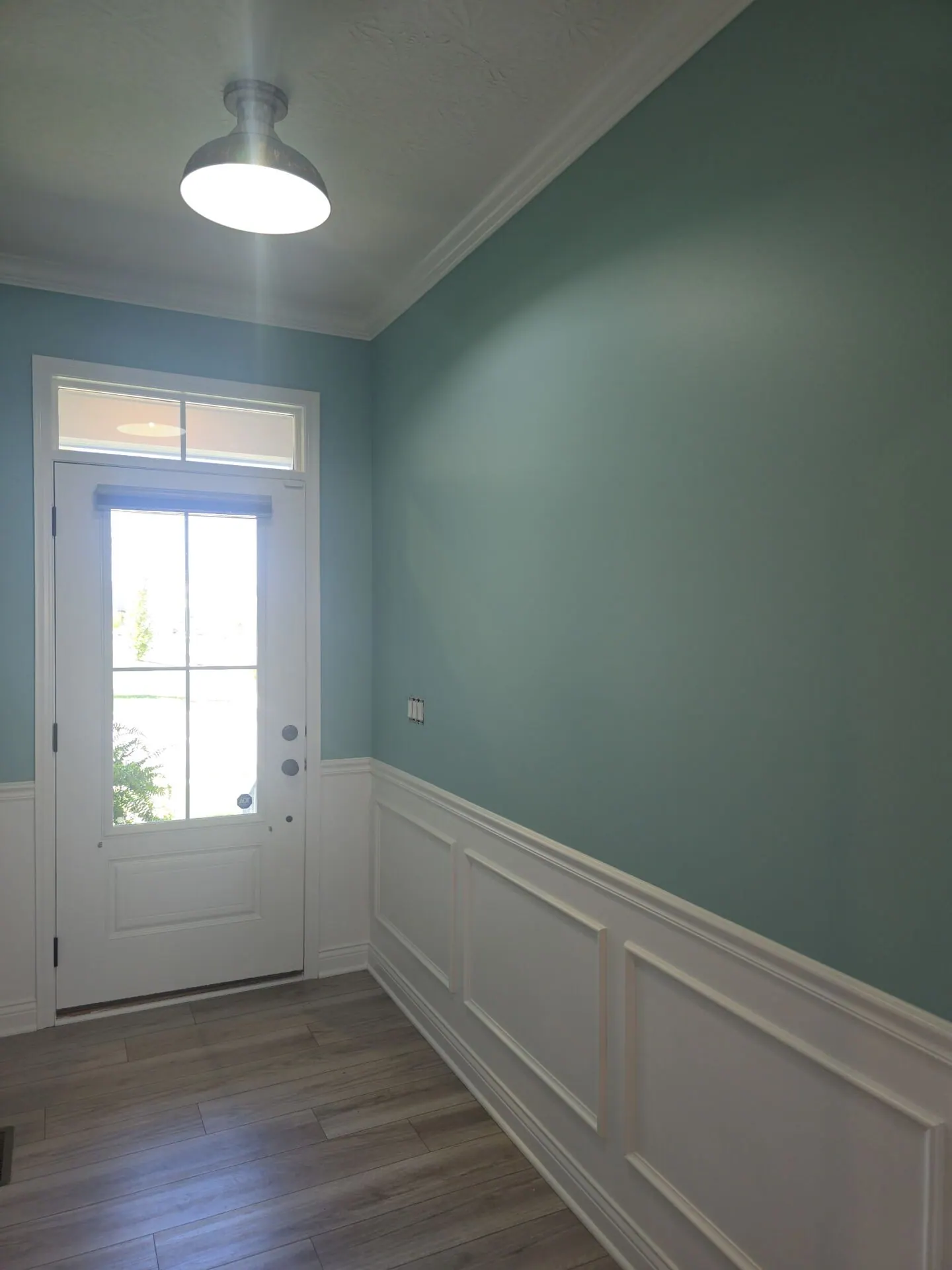 Mudroom entry with teal walls and white wainscoting