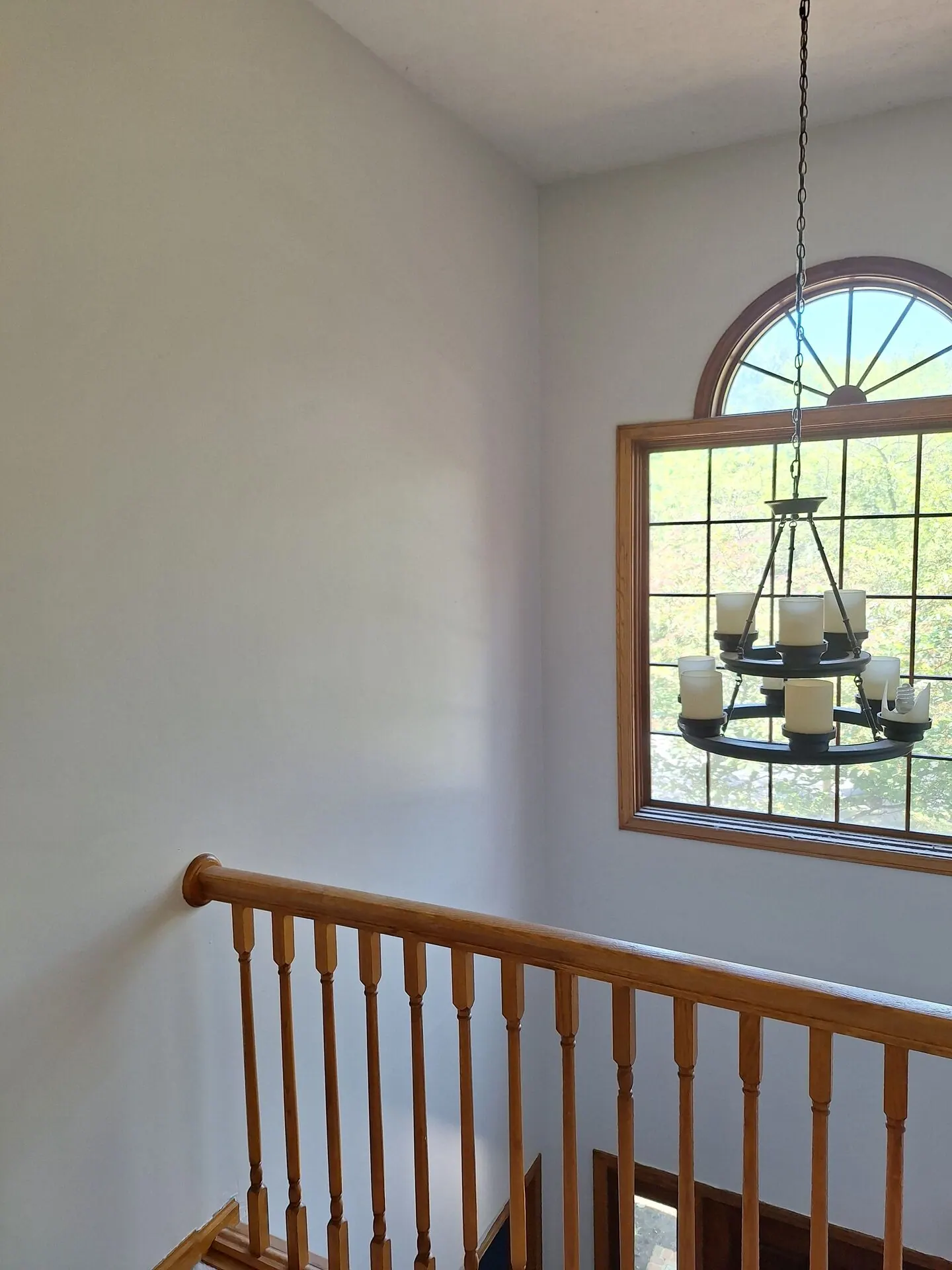 Two-story foyer with arched window and chandelier painted light gray