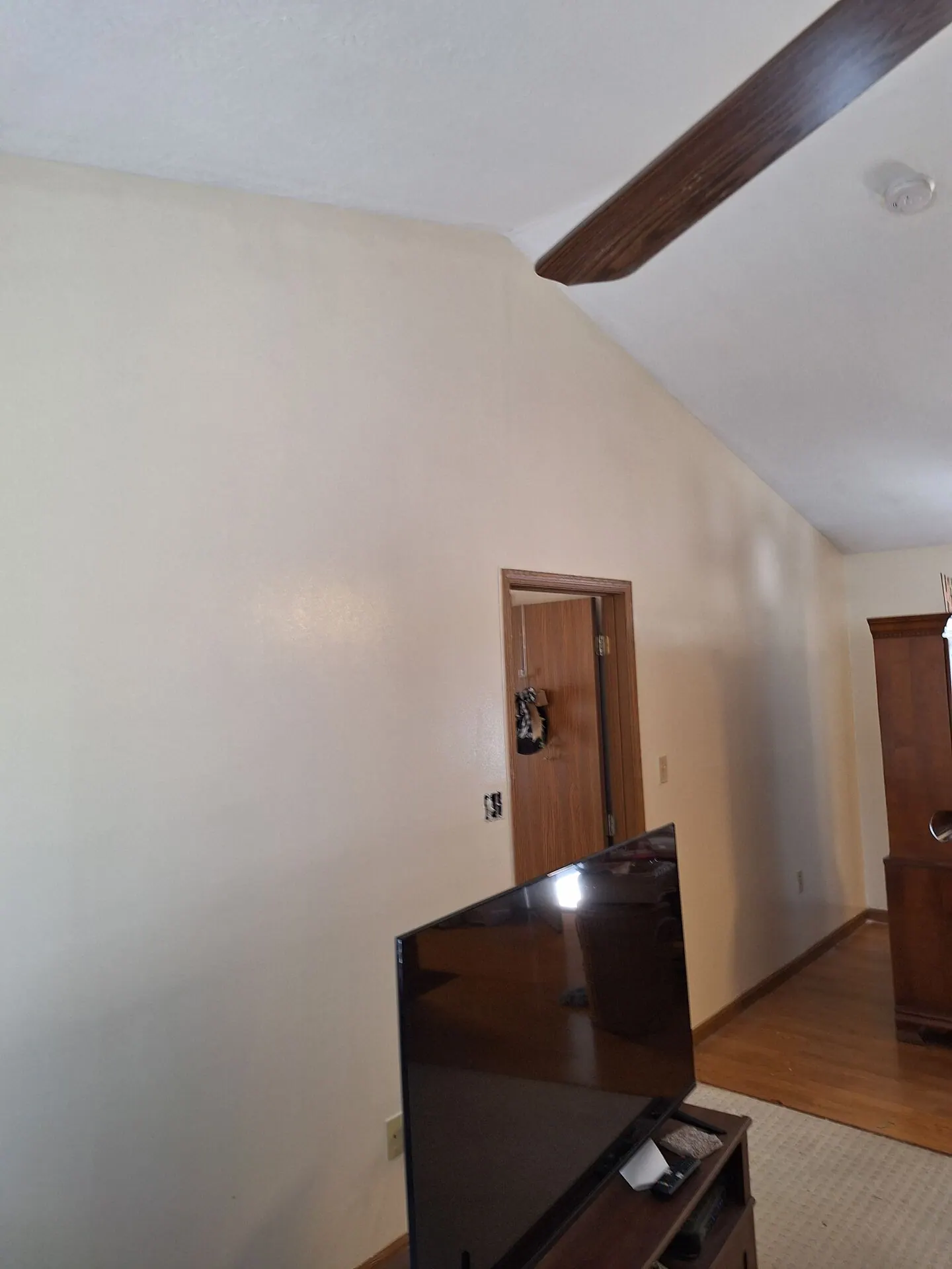 Vaulted wall with wood beam repainted warm white