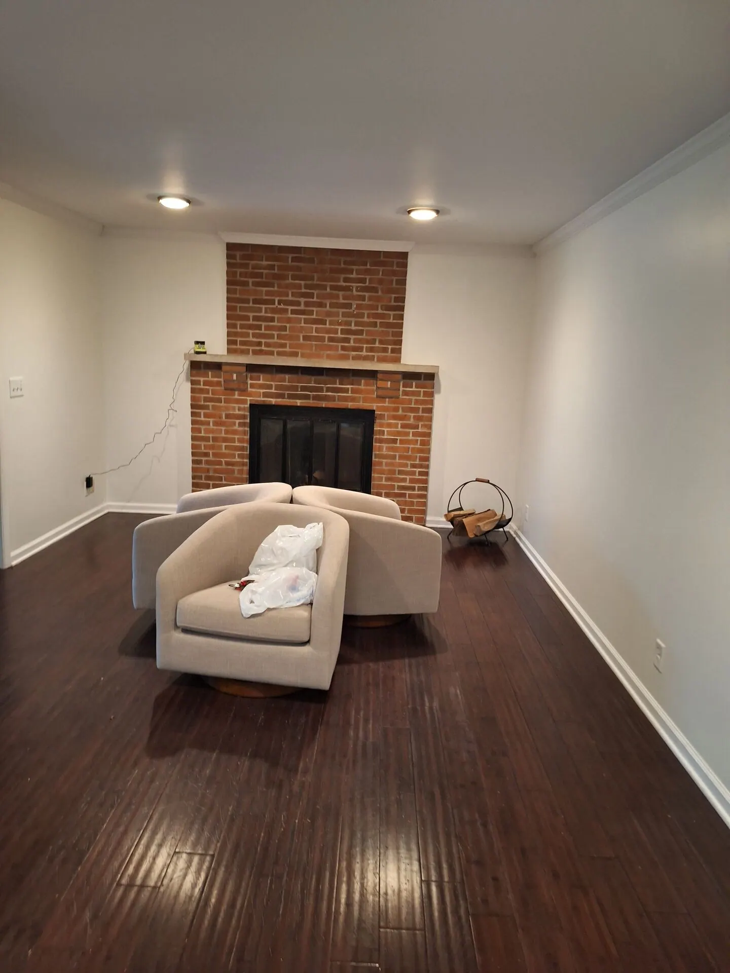 Long living room painted white with brick fireplace